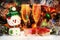 Merry snowman and wineglasses with sparkling wine on the background of a Christmas tree. balls, garlands, tinsel