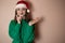 Merry surprised young woman wear xmas sweater Santa hat posing pointing hands arms aside indicate on workspace area isolated on