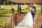 Merry wedding couple stands on a wooden bridge