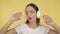 Merry woman sings the song. Energetic middle-aged woman in headphones on yellow background dancing
