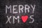 Merry xmas written on asphalt road, red stone in the shape of a heart