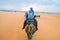 Merzouga, Morocco - APRIL 29 2019: Tourist smiling and facing the camera from a camel riding in the Sahara desert tour