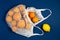 Mesh shopping bag with tangerines, lemons on a blue classic background.