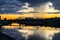 Mesmerizing blazing sunset over the mirror glossy surface of the Volga river, reflecting dramatic sky. City of Tver, Russia.