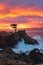 Mesmerizing colorful sunset over the foam waves crashing a rocky shore