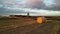 Mesmerizing drone view of a meadow field with huge hay bales on it at the golden sunset