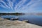 Mesmerizing  panoramic shot of a large lake under a blue sky with streams of clouds