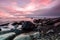 Mesmerizing pink sunset over the sea in a long exposure shot with rocky coast