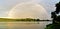 Mesmerizing shot of a perfect rainbow above the lake and natural landscapes