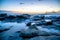 Mesmerizing shot of a rocky shore under the blue shades of the sunset