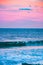 Mesmerizing shot of the waves of the ocean glimmering under the pink sky - great for wallpapers