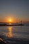 Mesmerizing vertical view of a scenic sunset above a rocky pier reflecting on water