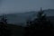 Mesmerizing view of the hills with wind turbines seen far away - dark foggy evening