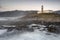 Mesmerizing view of the Larino lighthouse on a hill with foamy waves flooding on the rocky shore