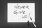 Message with black marker on white paper: Never Give Up
