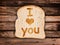 Message I love you written on a toasted slice of bread, on wooden planks
