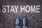 Message Stay home written on asphalt street with legs