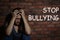 Message STOP BULLYING and abused teen girl crying near wall