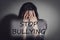 Message STOP BULLYING and abused teen girl crying near wall