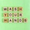 Message Wash Your Hands from wooden blocks on green background, hygiene concept