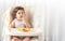 Messy baby girl eating cake.  Lovely infant girl holding a spoon, enjoying eating cake