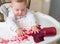 Messy and dirty baby is eating snack with hands