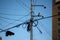 Messy electricity cable pole, blue sky in the background. High voltage electrical network, dangerously tangled