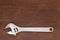 Metal adjustable wrench on a dark brown wooden board, top view, close up, copy space. Plumber and locksmith tools and works