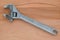 Metal adjustable wrench, tool for plumbers, on a brown natural wooden background