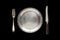 Metal antique plate, knife and fork isolated on a black background