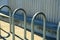 Metal bike rack arches for securing and chaining bicycle on side of metal building in urban downtown area of city