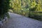 Metal black railing copying the slope of a paved park path with transverse gutters for water collection and drainage. hidden outle