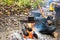 Metal black sooty mug on the grill on an open fire on the against the background of Hiking gear and autumn leaves.