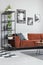 Metal bookshelf in grey Scandinavian living room interior with brown velvet sofa