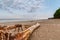 Metal brazier, the trunk of a fallen tree and a bench are stand on the deserted shore of a calm sea on a summer evening