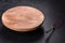 A metal cake blade with an empty brown cake stand on a dark concrete background