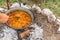 Metal cauldron boiling on a bonfire. Cooking on open fire, camping meal. Traditional preparation of goulash on a campfire