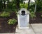 Metal and cement trash can with flowers and mulch