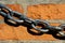 Metal chain lying on terracotta bricks wall