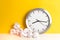 Metal clock with crumpled paper balls on a yellow background and wooden white table. Timing and thinking idea concept. Toned