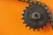 Metal cogwheel and chain on orange background.