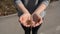 Metal coins fall into open female hands from a height outdoor on a sunny day