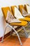 Metal construction chairs with yellow brown tapestry and white brown cushions standing in a row