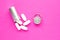 Metal container and pills on a pink background, close-up