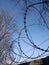 Metal cord with sharp edges on a wall made of rectangular stones under a clear blue sky