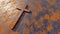 Metal cross on a rusted corroded metal or steel sheet background