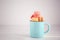 Metal cup with tasty colorful macarons on light background