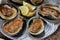 Metal dish with several baked oysters and slices of lemon