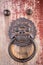 Metal door holder detail hanging on red wooden door. Figure of a guardian protector. Bulguksa buddhist temple close to the city of