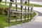 Metal fence construction made of shiny wet stainless pipes along road highway turn on copy space background of green grass